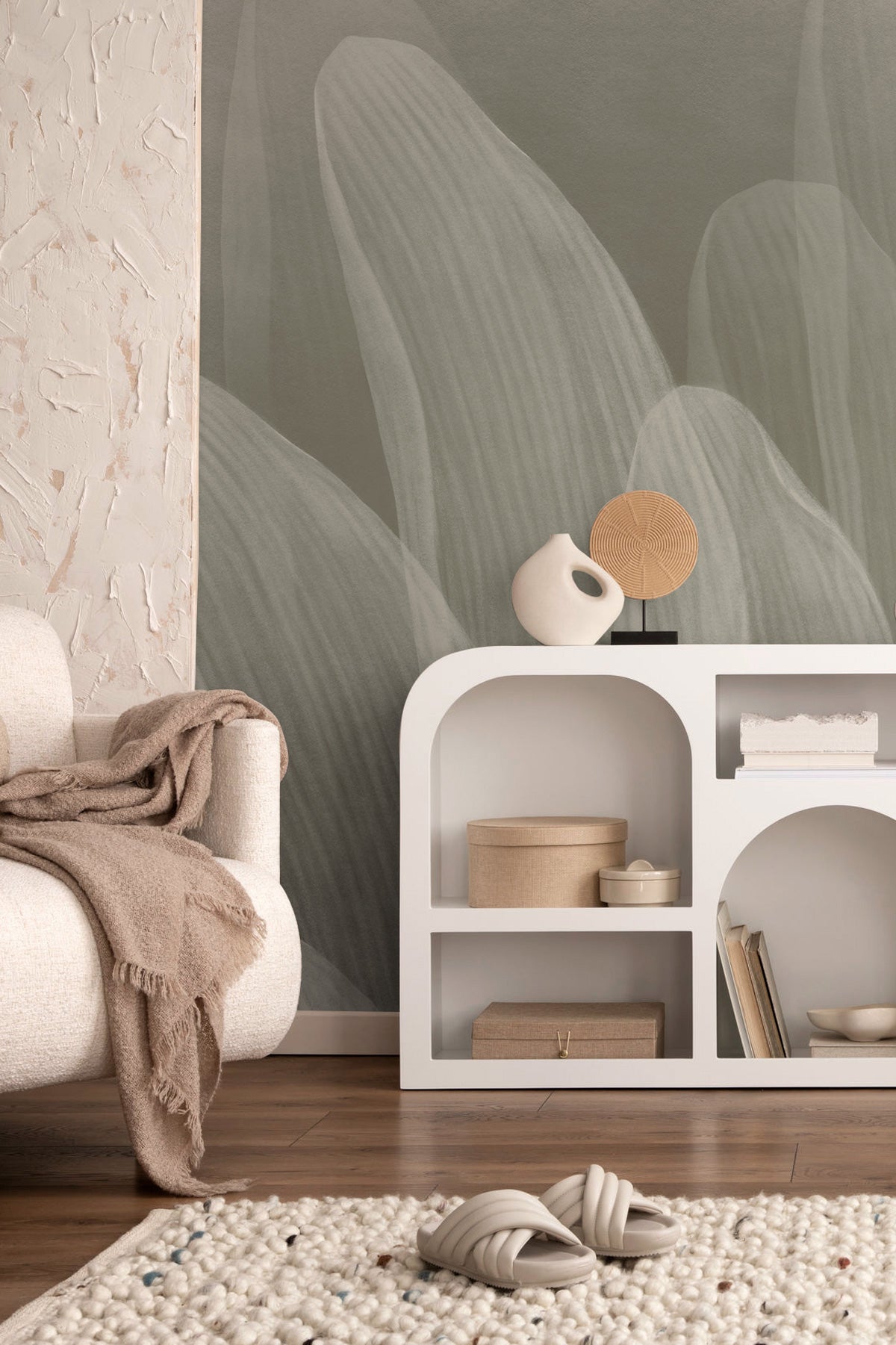 Elowen / Taupe wall mural in a modern living room with a white shelf and beige armchair.