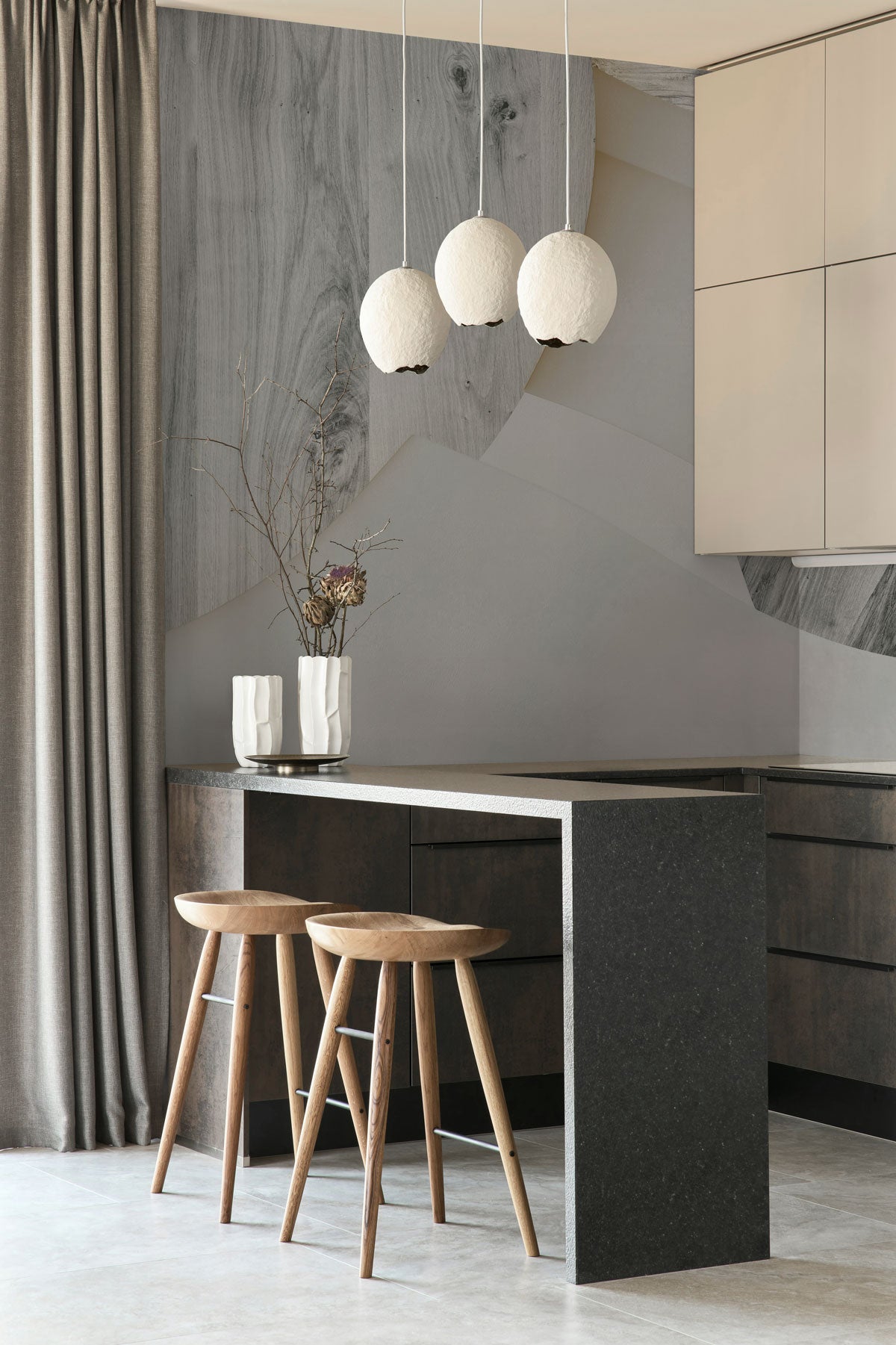 Astra Veil / Wood Wall Mural in a modern kitchen with a dark island, wooden stools.